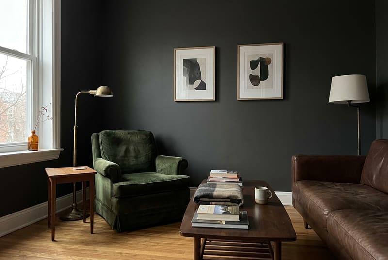Living room with charcoal walls, a green velvet armchair and a brown leather sofa